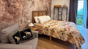 Una camera da letto con un letto, un divano, un comodino e vista sull'esterno.