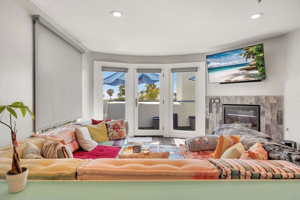 A living room with a sofa, a potted plant, and a flat-screen TV on the wall. - Santorini Escape in La Jolla! | Walk to the Beach (San Diego)