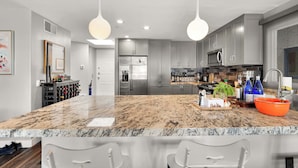A modern kitchen with granite countertops, stainless steel appliances, and pendant lighting. - Santorini Escape in La Jolla! | Walk to the Beach (San Diego)