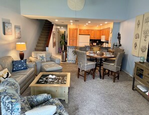 A living room with a sofa, coffee table, and dining area with chairs and a table. - Ocean Cove Retreat, 3-Min Walk to Beach! Perfect for families. (St. Augustine)