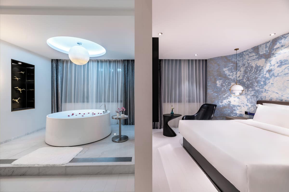 Une salle de bain moderne avec une baignoire sur pieds, un miroir rond et un luminaire fixé au plafond.