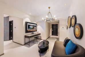 Ett modernt vardagsrum med en tv, en matplats och en soffa med kuddar.