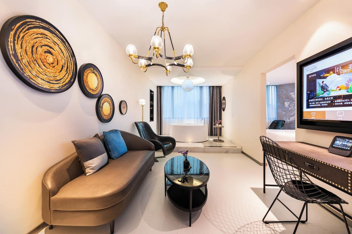 A modern living room with a sofa, a coffee table, a TV, and a desk with a chair.