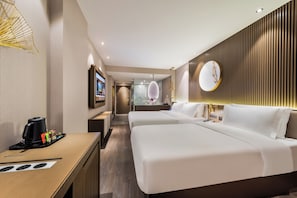 Une chambre dâhĂŽtel avec deux lits, un bureau avec une machine Ă cafĂ©, un miroir et un tĂ©lĂ©viseur fixĂ© au mur.