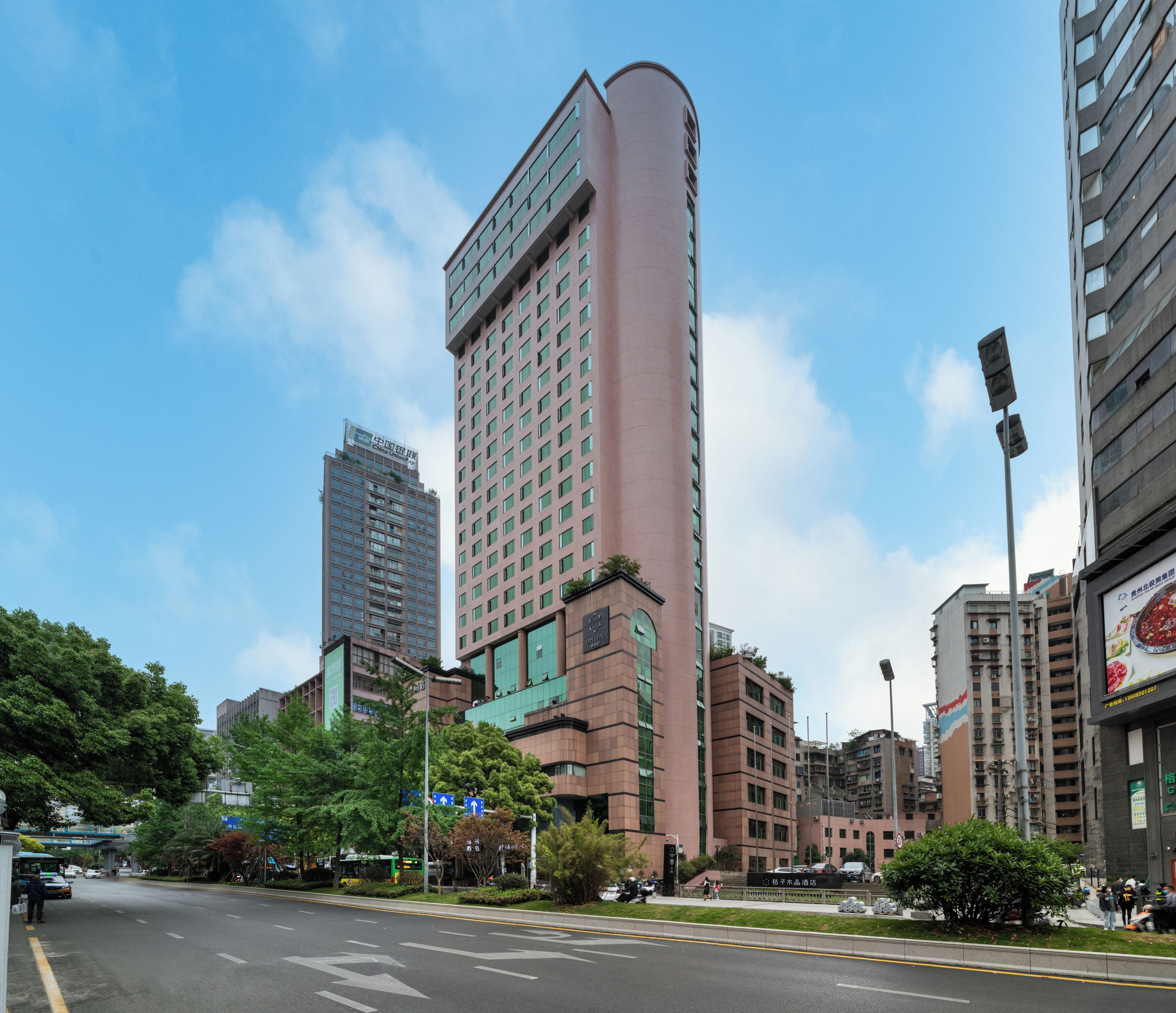 A cityscape with modern buildings, a clear sky, and a road with directional signs.