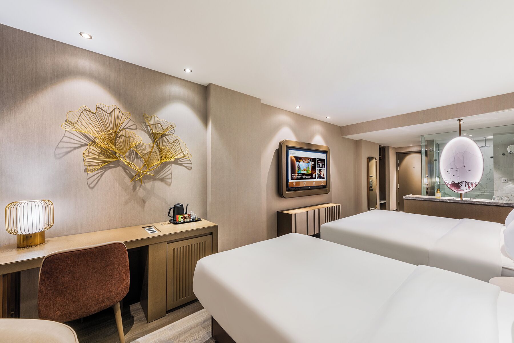 Habitación de hotel con dos camas, un escritorio con silla, un televisor montado en la pared y una lámpara de techo original.