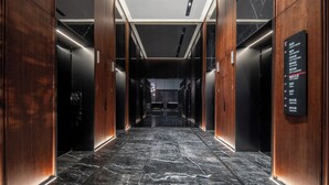 A modern elevator lobby with marble flooring, wooden paneling, and a sign listing amenities like guest rooms and city lobby. - IntercityHotel Chongqing SKLP (Chongqing)