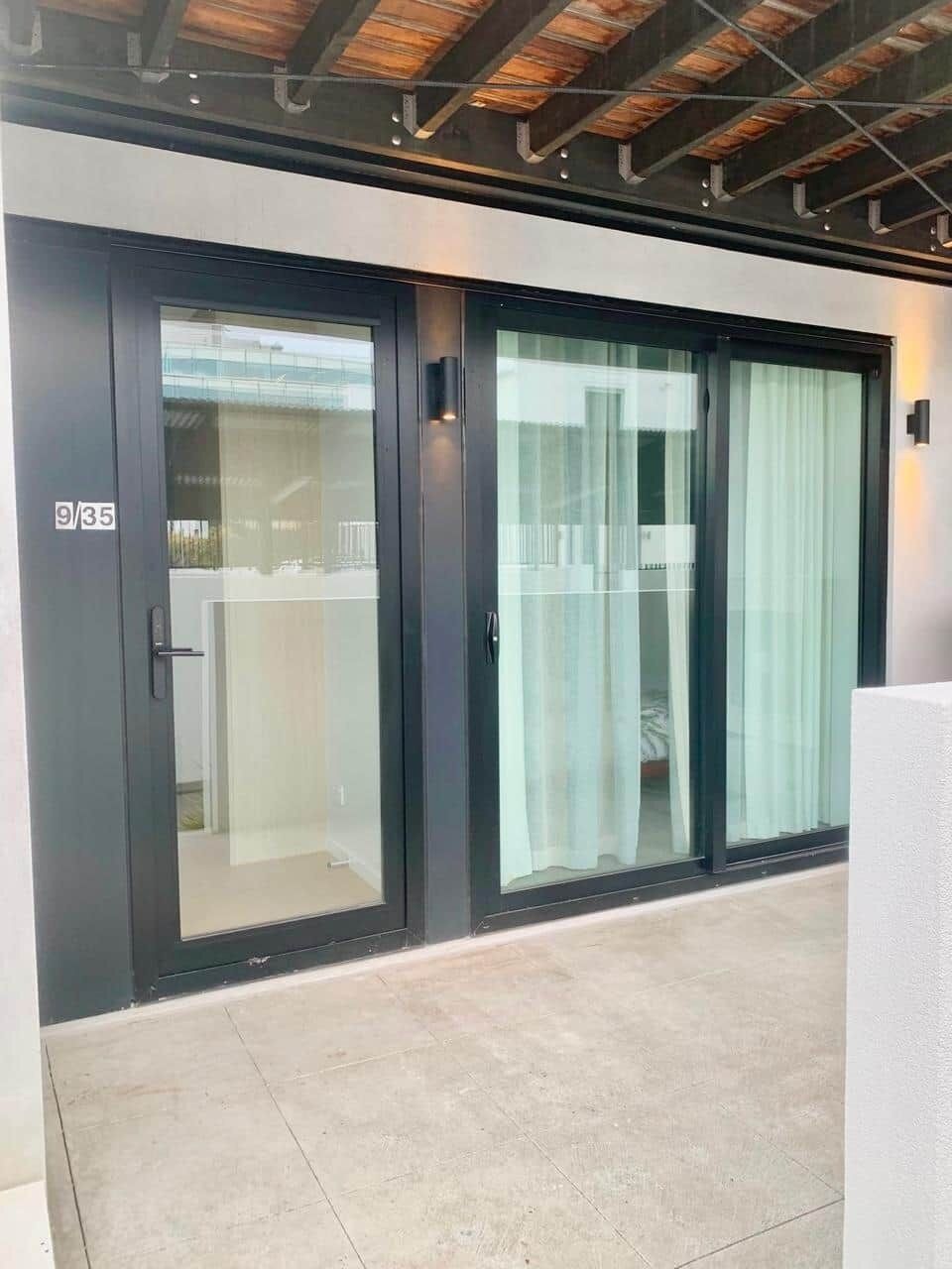 A modern building entrance with a glass door and a sliding glass door, both with a dark frame.