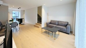 Un salon moderne avec un canapé gris, une table à manger en verre et une table basse.