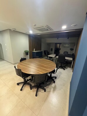 A conference room with a round table, chairs, and a small reception desk. - Casa Confortavel em Foz do Iguaçu (Foz do Iguaçu)