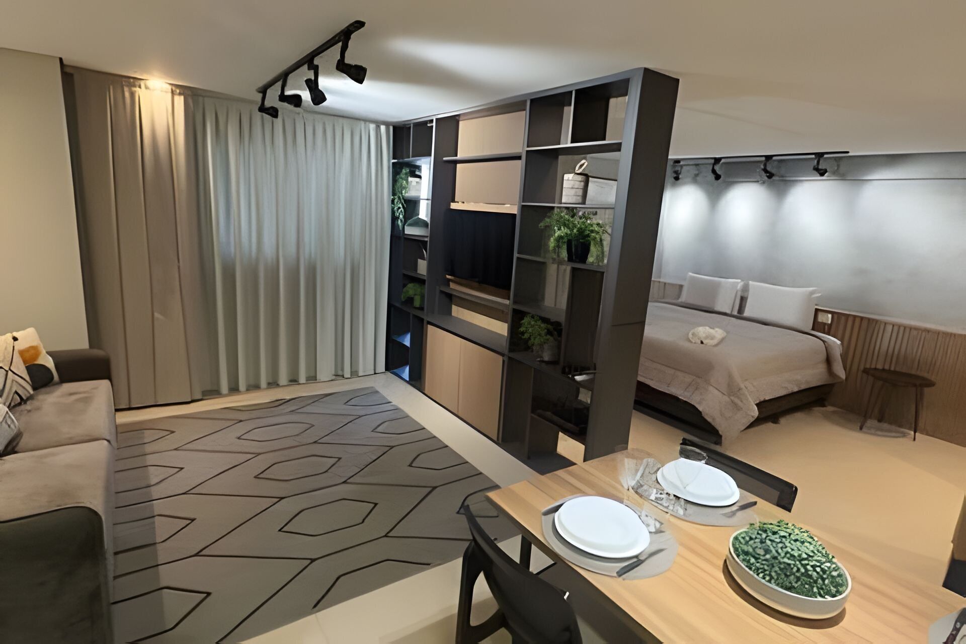 Quarto de hotel moderno com área de jantar, uma cama e uma estante embutida.
