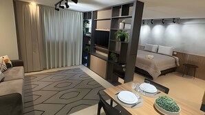 A modern hotel room with a dining area, a bed, and a built-in shelving unit. - Casa Confortavel em Foz do Iguaçu (Foz do Iguaçu)