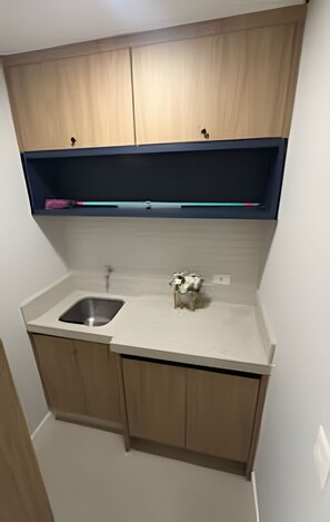 A small kitchen with wooden cabinets, a sink, and a countertop. - Casa Confortavel em Foz do Iguaçu (Foz do Iguaçu)