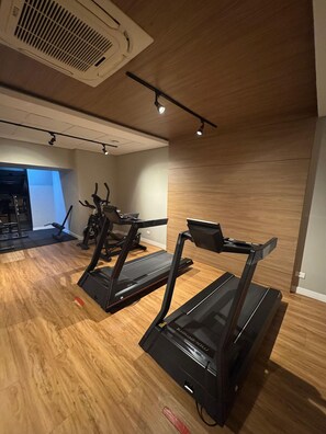 A gym with treadmills, exercise bikes, and a weight machine. - Casa Confortavel em Foz do Iguaçu (Foz do Iguaçu)