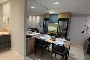 Una cocina moderna con comedor, equipada con refrigerador, estufa y asientos.