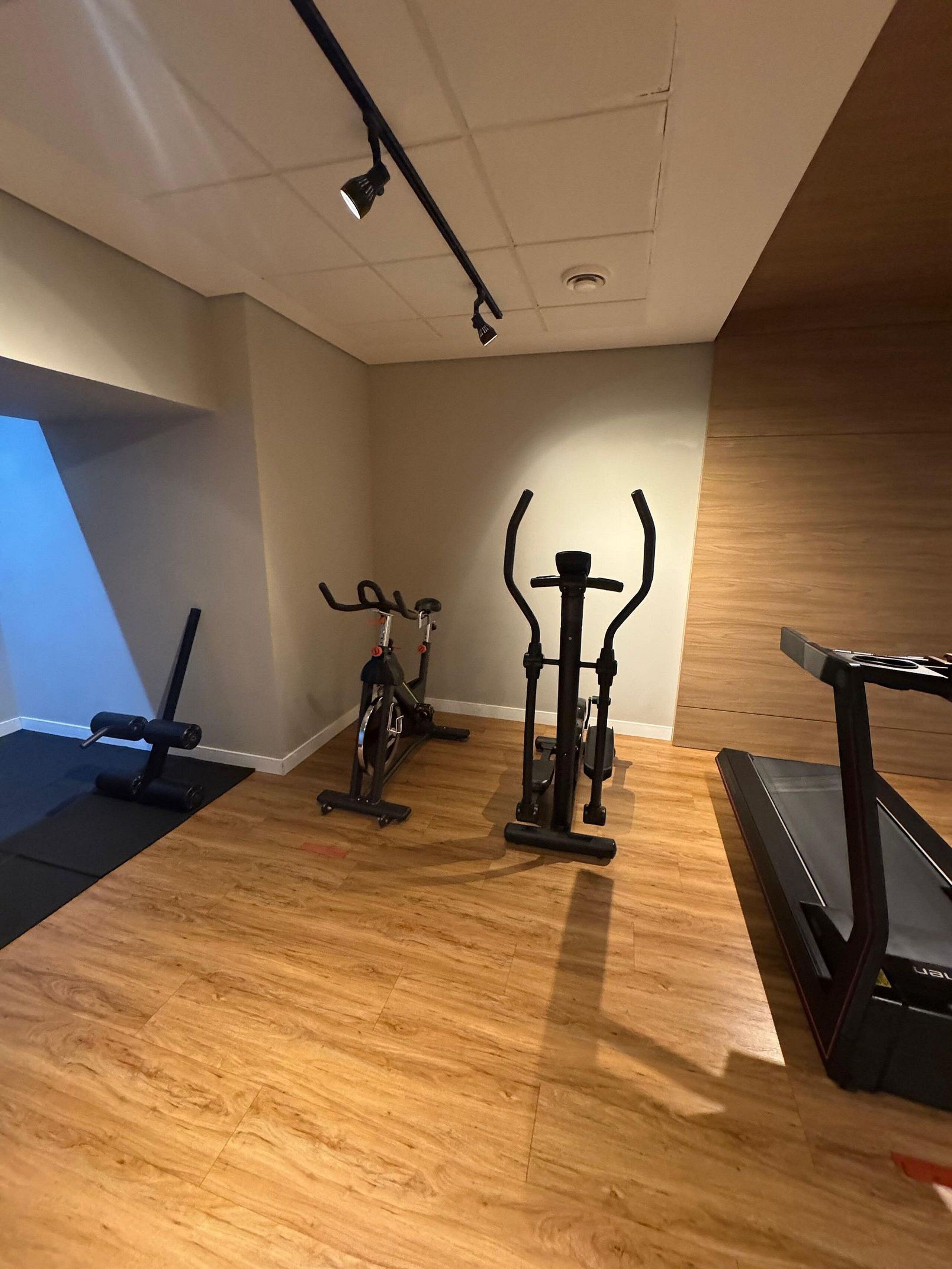A gym with exercise equipment including a treadmill, stationary bike, and weight machines.