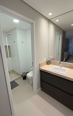 Un baño moderno con un espejo grande, un lavabo y un inodoro.
