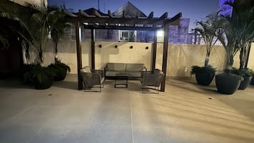 Un patio al aire libre con una pérgola de madera, asientos y plantas en macetas.