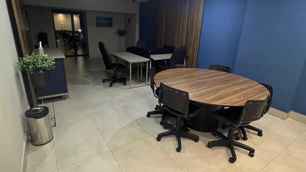 A conference room with a large round table, black office chairs, and a potted plant. - Casa Confortavel em Foz do Iguaçu (Foz do Iguaçu)