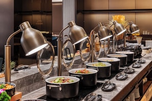A buffet setup with multiple food stations, each with a pot of food and a lamp above. - Crystal Hotel Chongqing Jialing River (Chongqing)