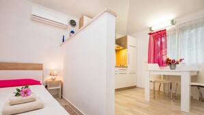 A hotel room with a bed, bedside table, lamp, and a view into the kitchen area. - Marisa Olive Grove - App Aria, Labin, Croatia (Labin)