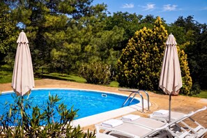 A swimming pool with lounge chairs and umbrellas, surrounded by greenery and trees. - Marisa Olive Grove - App Aria, Labin, Croatia (Labin)