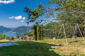 Ein Rasen mit Schaukeln, Blick auf einen See und ferne Berge.