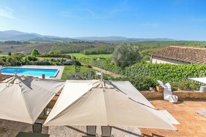 Ein Pool mit Sonnenschirmen, Blick auf die Landschaft und ein Gebäude mit einem Ziegeldach.