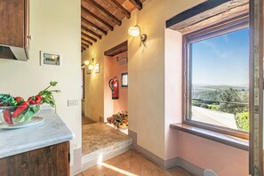 Eine Küche mit Marmorarbeitsplatte, einer Schüssel frischem Gemüse und einem Fenster mit Blick auf die Landschaft.