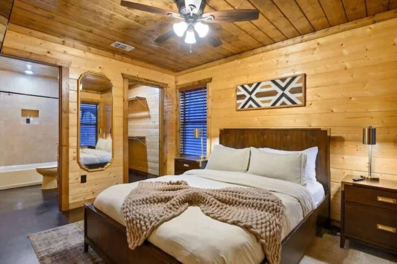 Un dormitorio con paneles de madera, una cama, un ventilador de techo y un espejo montado en la pared.