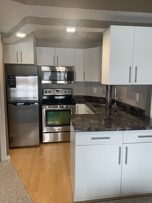 Una cocina moderna con electrodomésticos de acero inoxidable, armarios blancos y encimera de mármol.