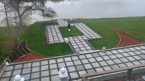 A park with a paved area, a body of water, and a tree. - One Bedroom Basement apartment on Red River bank (Selkirk)