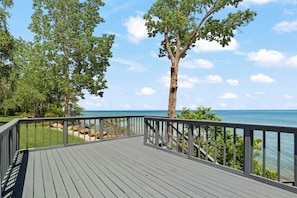 A wooden deck with a railing, overlooking a body of water and trees.