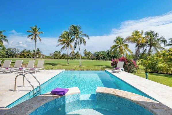 A swimming pool with lounge chairs, palm trees, and a clear sky. - Villa Casa Bonita Punta Cana (Punta Cana)