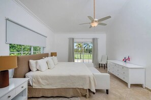A bedroom with a bed, bedside tables, a desk, a ceiling fan, and a view of the outdoors. - Villa Casa Bonita Punta Cana (Punta Cana)