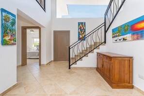A staircase with a wooden cabinet and artwork on the walls. - Villa Casa Bonita Punta Cana (Punta Cana)