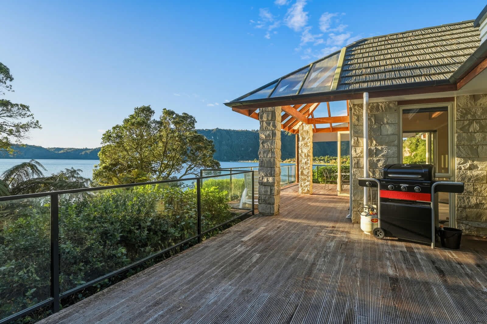 Ein Balkon mit einer Steinmauer, einem Grill und Blick auf den See.