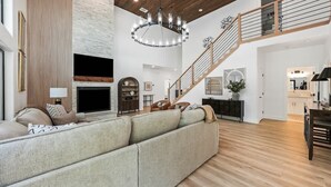 Ein geräumiges Wohnzimmer mit einem großen Ecksofa, einem Kamin, einer Treppe und einem Essbereich.