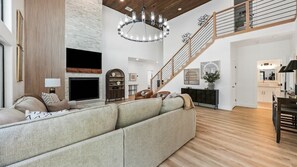 Ein geräumiges Wohnzimmer mit einem großen Ecksofa, einem Kamin, einer Treppe und einem Essbereich.