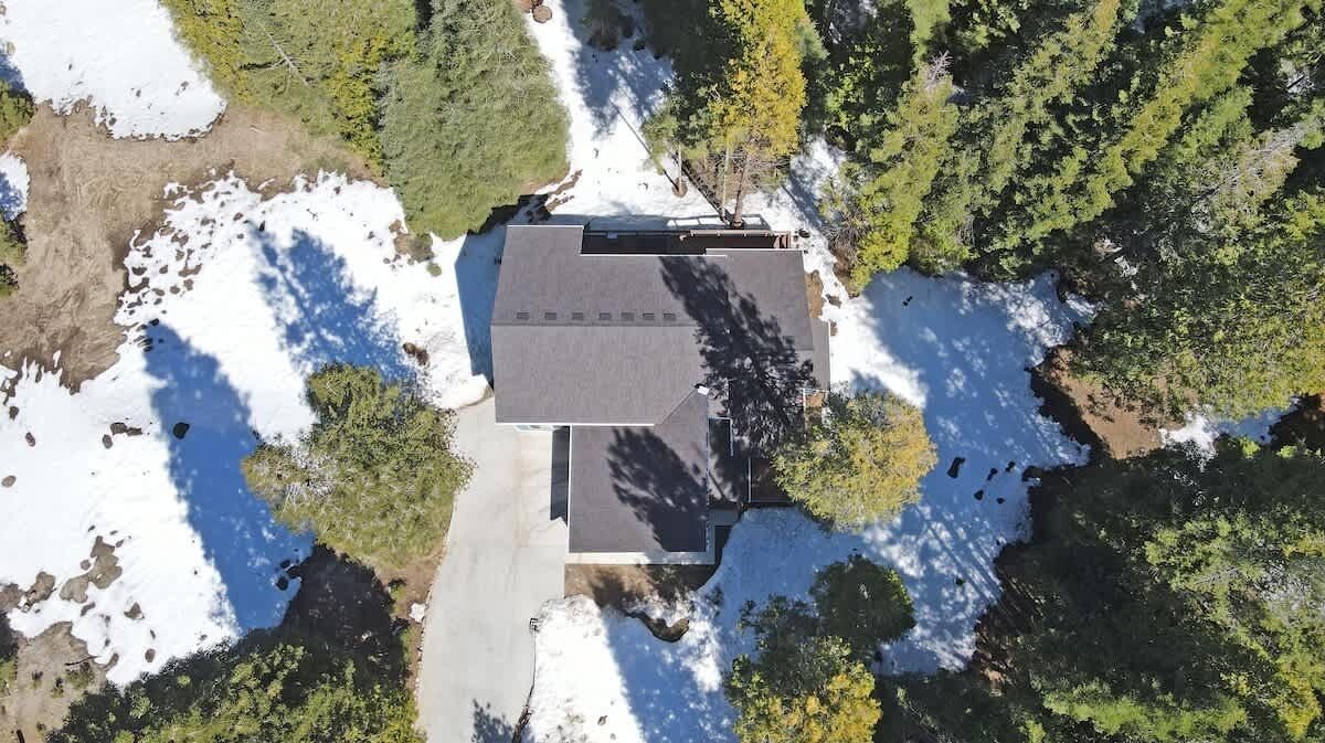Luchtbeeld van een gebouw met een plat dak, omgeven door sneeuwvlekken en weelderige begroeiing.