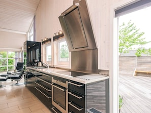 A modern kitchen with a large island, built-in oven, and a high chimney. - 5 Star Holiday Home in Odder (Odder)