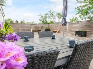 A patio with a table and chairs, a wooden fence, and a bench.