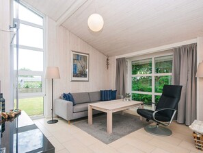 A room with a sofa, a chair, a table, and a large window with curtains. - 5 Star Holiday Home in Odder (Odder)