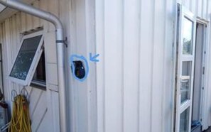 Fachada de prédio com janela, porta e uma seta azul apontando para um buraco na parede.
