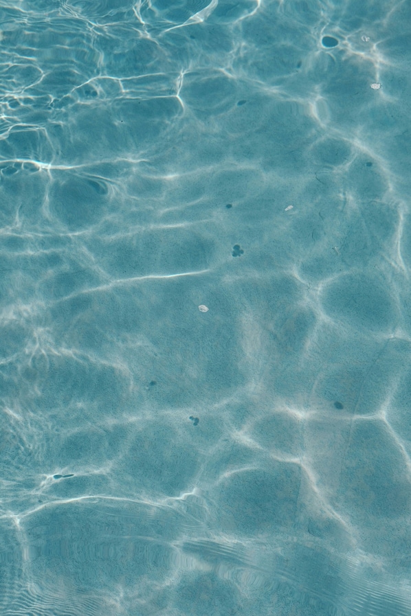 A clear view of a swimming pool's surface with visible ripples and reflections.