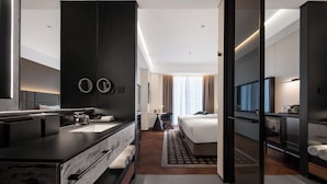 Camera d'albergo moderna con un letto grande, bagno separato con lavabo, televisione e vista sulla città.
