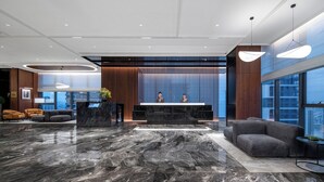 Una hall moderna con reception, zona relax e ampie finestre.