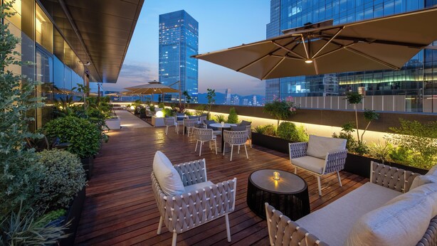 Una terrazza sul tetto con posti a sedere all'aperto, vista sullo skyline cittadino e architettura moderna.