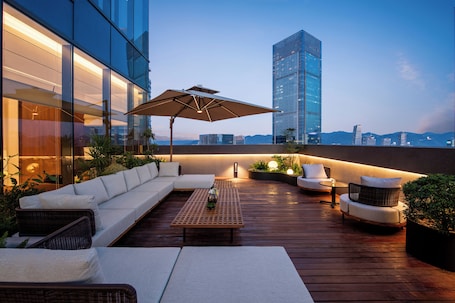 A rooftop terrace with a sofa, chairs, a table, and an umbrella.. IntercityHotel Chongqing jiangbeizui