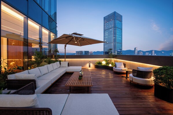 A rooftop terrace with a sofa, chairs, a table, and an umbrella. - IntercityHotel Chongqing jiangbeizui (Chongqing)